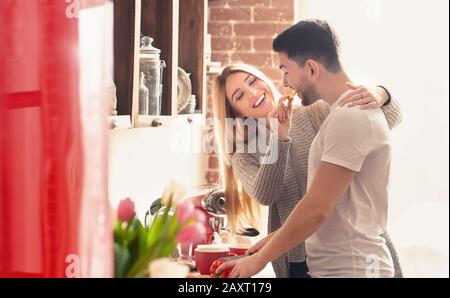 Donna che alimenta il suo ragazzo con un pezzo di paprika prima della colazione Foto Stock