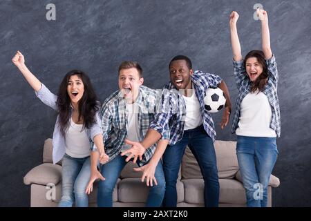 Amici multietnici eccitati che guardano il calcio a casa Foto Stock