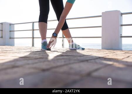 Vista laterale parte bassa di una donna caucasica matura di mezza età che lavora su una passeggiata in una giornata di sole, allungando Foto Stock