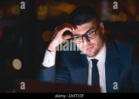 Ritratto Dell'Uomo D'Affari Al Laptop Che Lavora Durante La Notte Seduto In Ufficio Foto Stock