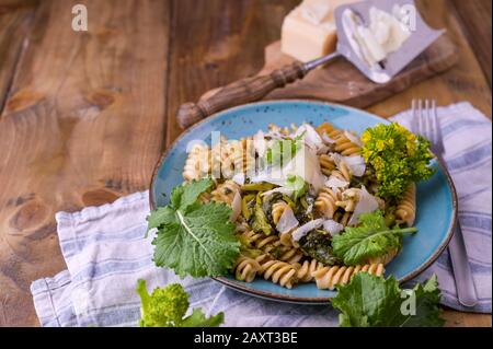 Cime di rapa in un piatto con parmigiano su un tavolo di legno. Cucina tradizionale del sud d'Italia, dalla Puglia. Foto in stile rustico. Foto Stock