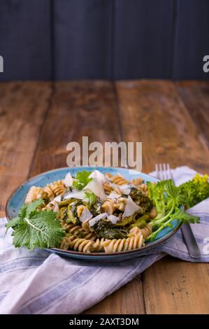 Cime di rapa in un piatto con parmigiano su un tavolo di legno. Cucina tradizionale del sud d'Italia, dalla Puglia. Foto in stile rustico. Foto Stock