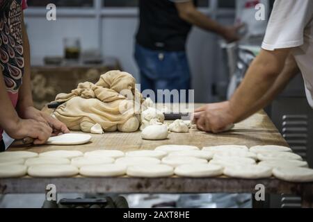 Uomo e donna che fanno pane da pasta di farina in una piccola panetteria locale sulla strada nel quartiere musulmano, Xian città, Cina Foto Stock