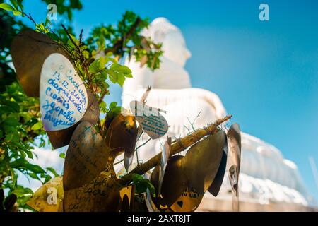 Nakkerd Hill, Phuket/Thailand-15December2019: Campanelli di preghiera a forma di cuore dorato che pendono insieme in una fila con le note spirituali della gente scritte su di loro Foto Stock