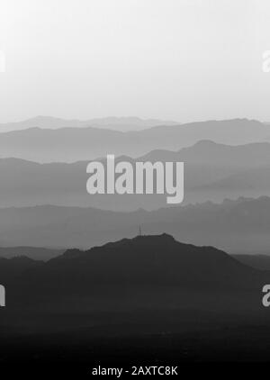 Una fotografia in bianco e nero di una scena del mattino presto di alcune colline lontane con nebbia. Foto Stock