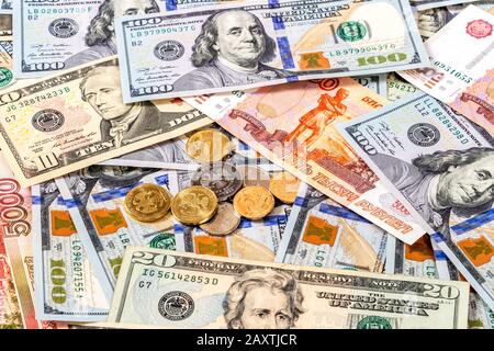 Varie monete giacenti su diverse banconote in valuta dollari e rubli vicino. Background di soldi Foto Stock