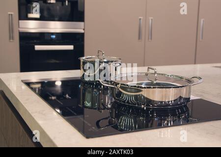 Metallo moderno zuppa di pentola o padella con maniglie nere su un fornello  ad induzione. Gocce di acqua bollente sono sulla superficie interna del  vetro trasparente coperchio Foto stock - Alamy