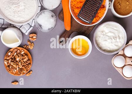 Ingredienti da forno per una farina di torta di carote, burro, zucchero di canna, carote grattugiate, noci e altro Foto Stock