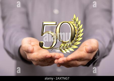 Numero 50 accanto ad un picco d'oro sulla mano di qualcuno Foto Stock