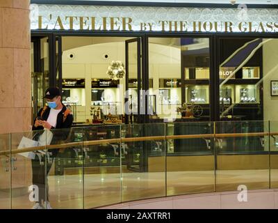 Ion ORCHARD, SINGAPORE – 8 FEB 2020 – un giovane acquirente asiatico cinese che indossa una maschera facciale fuori l'Atelier by The Hour Glass, una boutique di orologi di lusso Foto Stock