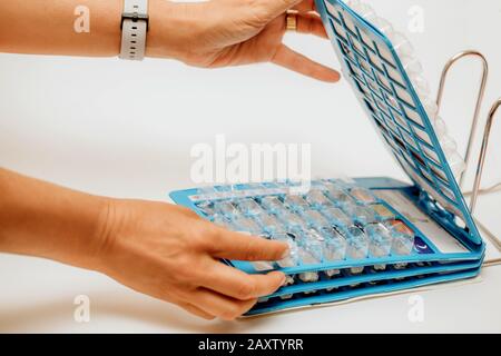 La mano della donna che prende le pillole dal blister quotidiano della confezione. Farmaci per pazienti in ospedale. Foto Stock