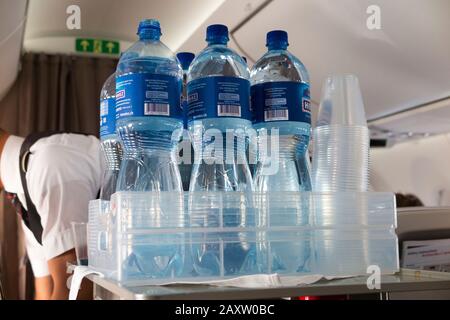 Membro dell'equipaggio di cabina con il carrello delle bevande idriche consegna bevande rinfrescanti ai passeggeri in economia nei loro posti su un aeromobile Bombardier aereo / aereo / aereo / aereo. (112) Foto Stock