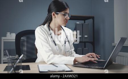 Medico che usa il computer portatile al lavoro Foto Stock