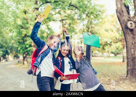 Bambini felici che celebrano il successo con le mani alzate. Tre ragazzi felici che celebrano ottimi risultati a scuola. Foto Stock