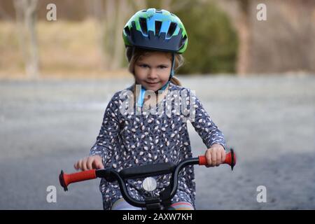 determinata bambina imparare a guidare la bicicletta con ruote di allenamento in paese Foto Stock