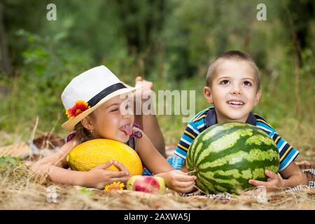 La bambina mostra la lingua ad un ragazzo. Bambini in un pic-nic nella foresta. I bambini si divertono durante le vacanze estive. Foto Stock