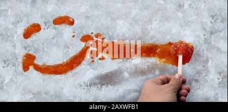 Il sorriso felice del viso dell'acero taffy come il sap dell'albero bollito e lo sciroppo bollito dolce sulla neve come coltura dell'alimento della molla dal Quebec Ontario Canada e dal New England. Foto Stock