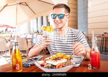 Uomo allegro mangiare gyros pita nel caffè. Cucina di strada mediorientale Foto Stock