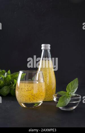 Cocktail blu con semi di basilico e succo d'arancia tropicale in vetro su sfondo nero. Primo piano. Formato verticale. Foto Stock