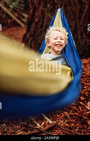 Sorridente bambino con capelli ricci in un'amaca Foto Stock