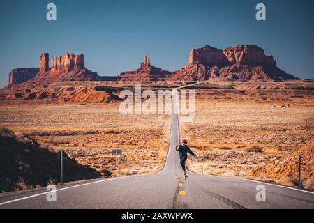 Ragazza sta saltando sulla strada vicino a Forrest Gump Point, Monument Valley Foto Stock