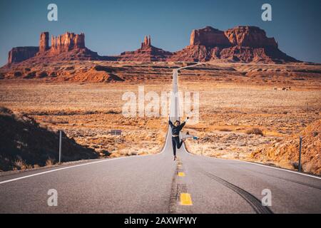 Ragazza sta saltando sulla strada vicino a Forrest Gump Point, Monument Valley Foto Stock