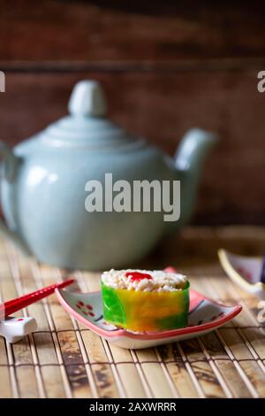 Primo piano di sushi caramella su un tappeto di bambù con teiera blu. Foto Stock