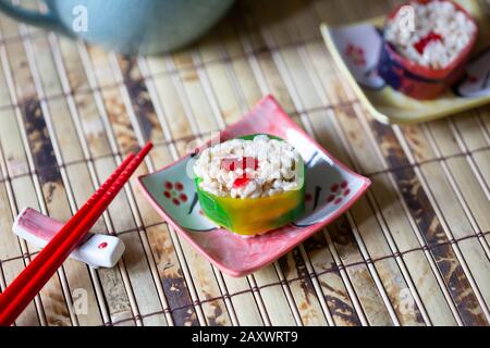 Primo piano di sushi caramella e bacchette su un tappeto di bambù. Foto Stock