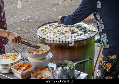 Donna che fa la frittella di gamberetti piccola al fornitore vietnamita di cibo di strada Foto Stock