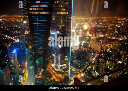 Veduta aerea di Shanghai di notte e riflessioni della luce della città e degli interni dell'edificio in vetro finestra. Foto Stock