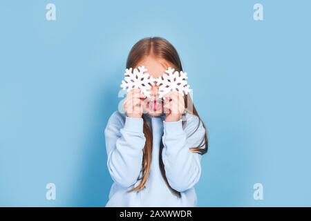 Bambina che tiene le mani fiocchi di neve davanti ai suoi occhi Foto Stock