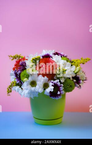 Bouquet di rose e margherite su sfondo azzurro e rosa con cornice in legno e spazio per il testo. Vista dall'alto. Concetto di evento. Foto Stock