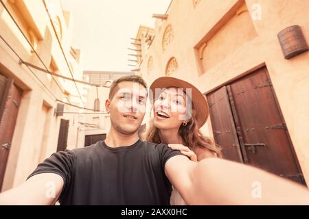 Una coppia felice prende un selfie sullo sfondo dell'antica architettura araba nella città vecchia di Dubai. Concetto di viaggio luna di miele Foto Stock