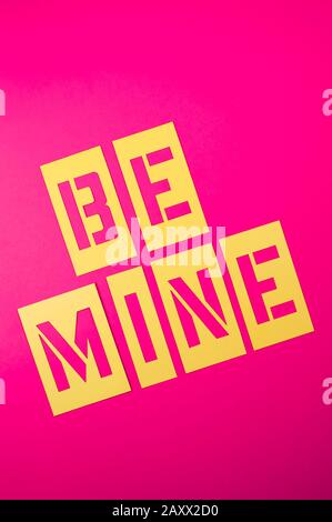 Be Mine San Valentino messaggio scritto in giallo stencil scritta su sfondo rosa brillante Foto Stock