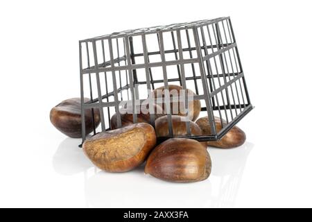 Gruppo di sette castagne marroni commestibili intere in cestello di plastica nero isolato su sfondo bianco Foto Stock