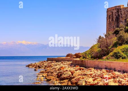 Tramonto vista mare, antiche mura del castello e cime di neve di montagna panorama in Messinia, Peloponneso, Grecia Foto Stock