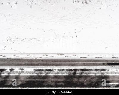 vista aerea delle impronte sulla strada innevata della strada in inverno Foto Stock
