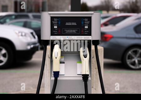 Stazione di ricarica per veicoli elettrici con vista sul parcheggio di diverse auto e altre automobili in background Foto Stock