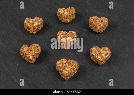 Gruppo di sette cuore di cereali marrone intero sano con cacao su pietra grigia Foto Stock