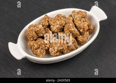 Molto cuore di cereale marrone intero e sano con cacao in bianco ovale ciotola di ceramica su pietra grigia Foto Stock