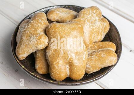 Lotto di pan di zenzero marrone dolce intero in ciotola di ceramica scura su legno bianco Foto Stock