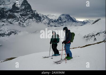 Due sciatori di backcountry nell'Oberland bernese in Svizzera. Eiger North Face è dietro di loro. Foto Stock