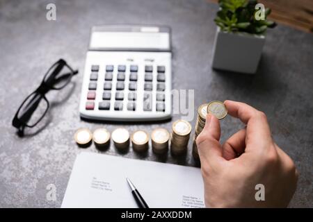 Persona Che Fa Il Calcolo Con Le Monete Impilate Sulla Scrivania Foto Stock