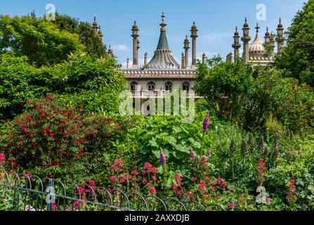 il padiglione di brighton nascosto parzialmente dietro gli alberi nei giardini del parco con solo le torri e i minareti che mostrano sopra la linea degli alberi. Foto Stock