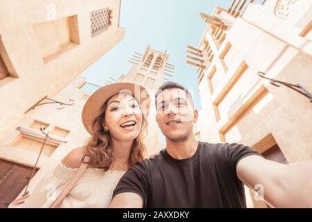 Una coppia felice prende un selfie sullo sfondo dell'antica architettura araba nella città vecchia di Dubai. Concetto di viaggio luna di miele Foto Stock