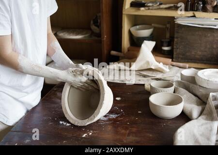 Mani femminili tenere una ciotola per il colaggio di prodotti di argilla Foto Stock