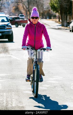 Donna attraente a cavallo della sua bicicletta; piccola città di montagna Salida; Colorado; Stati Uniti Foto Stock