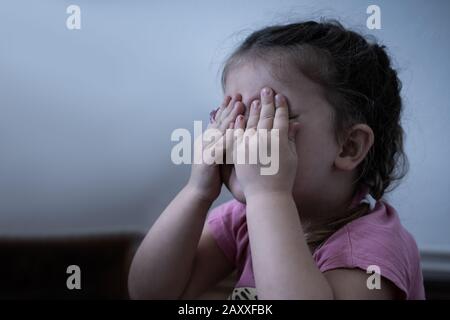 Bambina piangere. Molto ragazza triste che copre i suoi occhi Foto Stock