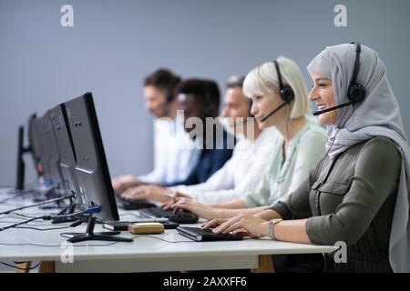 Femmina positivo Customer Services Agent con cuffia a lavorare in un Call Center Foto Stock