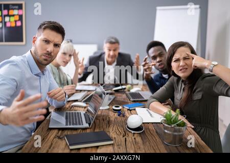 Un gruppo di dirigenti aziendali lamenta verso la telecamera in ufficio Foto Stock